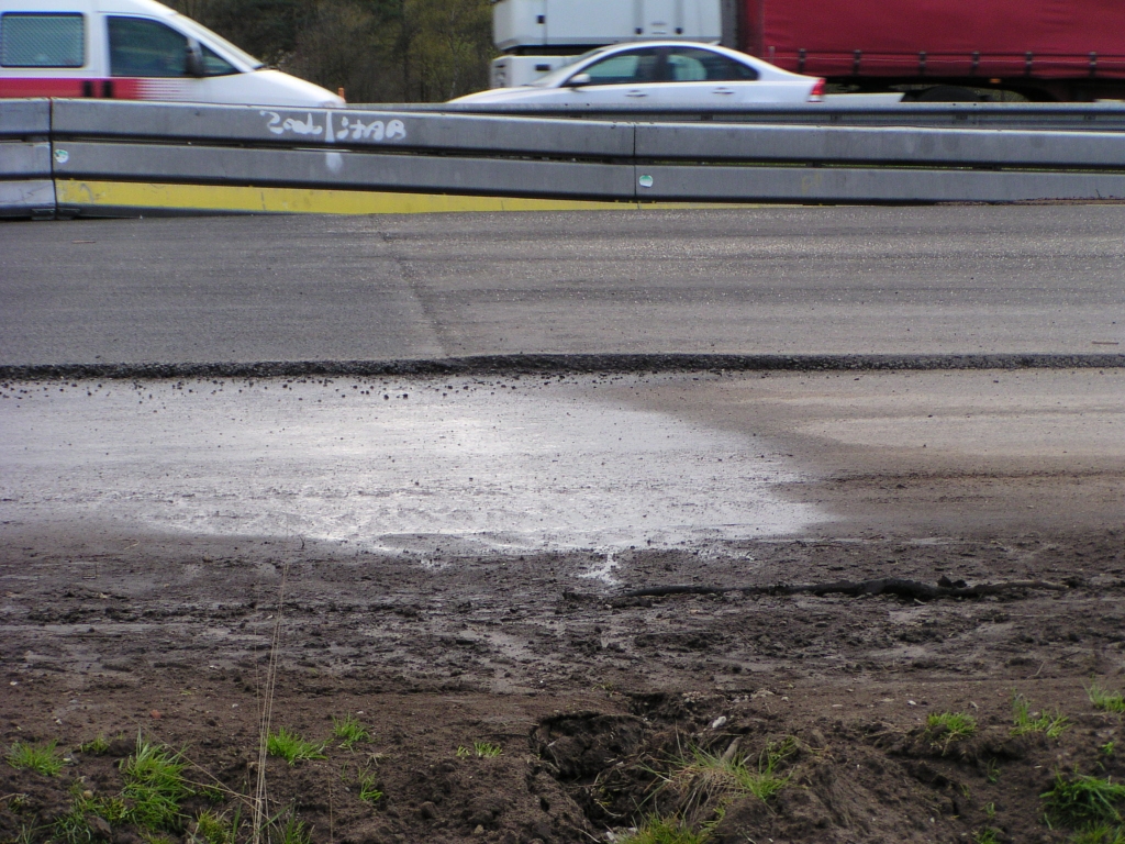 p4150007.jpg - ZOAB heeft het hemelwater geloosd op de onderlaag van dicht asfalt, zodat de plas blijft liggen. Dit effect is er niet rechts van de naad tussen een ZOAB en dicht asfalt toplaag.