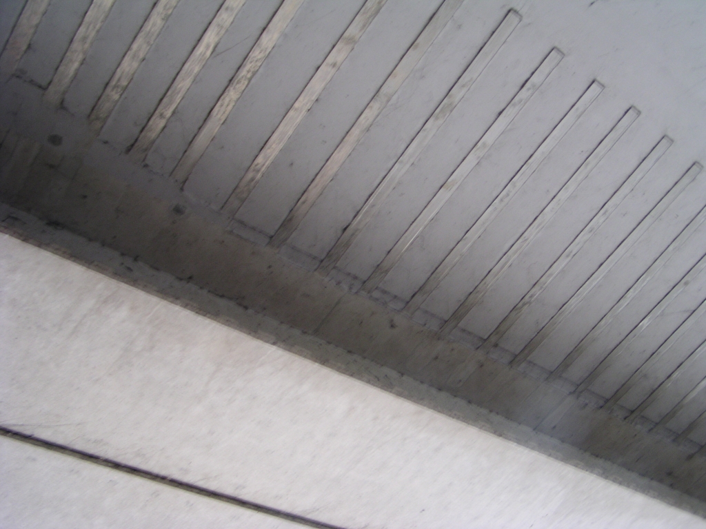 p4300034.jpg - Detail van een soort metalen strippen die mogelijk een rol spelen bij het verbinden van de verbredingen aan de oude brug. Mysterie (voor mij althans) is waarom men, ondanks de beschreven verbredingen, in de negentiger jaren van de vorige eeuw heeft besloten twee nieuwe bruggen te bouwen aan weerszijden van de verbrede brug ten behoeve van de in- en uitvoegers voor de aansluiting Veldhoven. Misschien waren de boogstralen te krap? Dat men toen reeds ging ombouwen naar 2x3 met vluchtstroken is onwaarschijnlijk - geen enkele andere aansluiting op de randweg is onder handen genomen in die tijd. Al met al ligt de oorspronkelijke verbreding van de brug er al jaren ongebruikt bij, zoals mooi te zien is in  Live Maps , maar komt nu mooi van pas bij de geeiste ruimtereservering voor 2x3 in het huidig project. Degene die de nieuwe bruggen voor de af- en toeritten heeft verzonnen ziet zijn investering maar in beperkte mate behouden blijven.