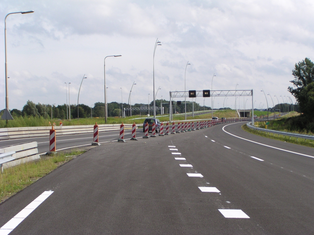 p8100047.jpg - Op een paar honderd meter van KW 6 komt de oude verbindingsweg uit op de nieuwe. Het verkeer gaat vervolgens onder KW 6 door naar de oude hoofdrijbaan. Deze situatie bestaat al enige maanden. Bij de actie van 15 augustus zal in plaats daarvan rechts van KW 6 de nieuwe parallelbaan worden opgereden. Het wegvakje onder KW 6 blijft dan ongebruikt tot de nieuwe hoofdrijbaan klaar is. Mocht het wegvak waar we nu opstaan ook de 15e in gebruik worden genomen dan kunnen al die bakens weg en een barrier geplaatst aan de linkerkant.  week 200829 