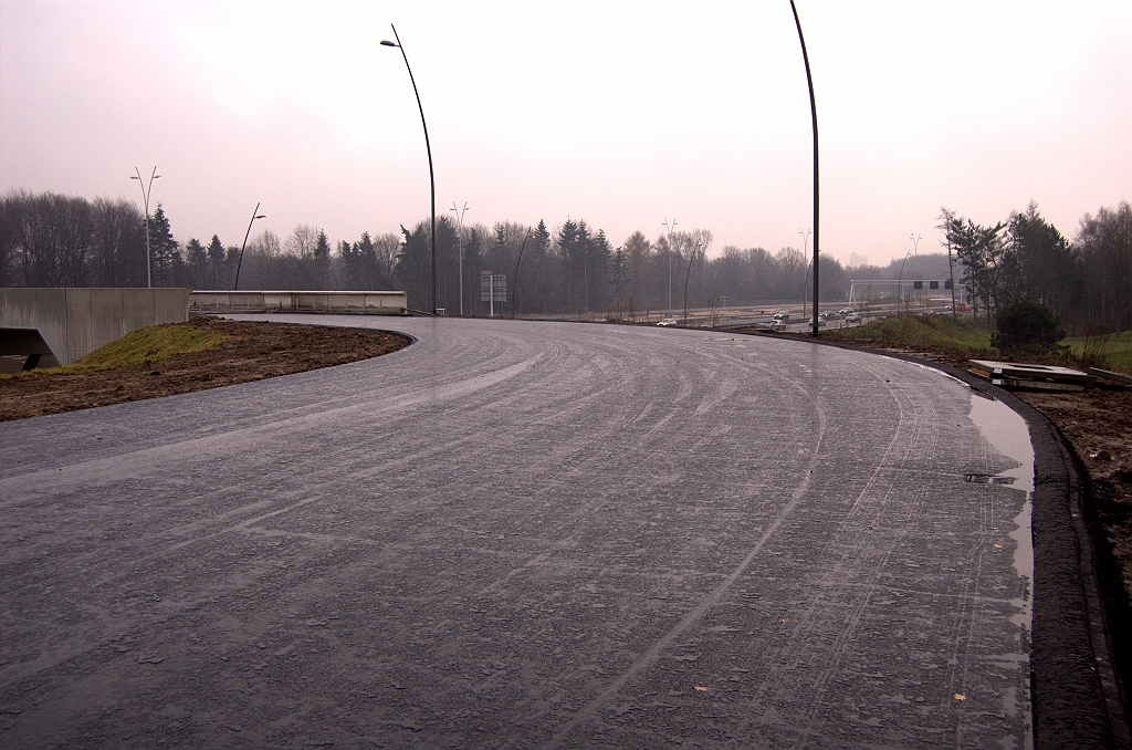 20081130-140521.jpg - Bovenaan de afrit de eerste bocht in de Strijpse Chicane, die behoudens de (open?) toplaag geheel van asfalt voorzien is, inclusief geintegreerde richels voor de waterhuishouding. Nog geen tekenen van geleiderails of zwaardere maatregelen tegen uit de bocht vliegen. Het talud ter rechterzijde is flink steiler dan normaal.  week 200847 