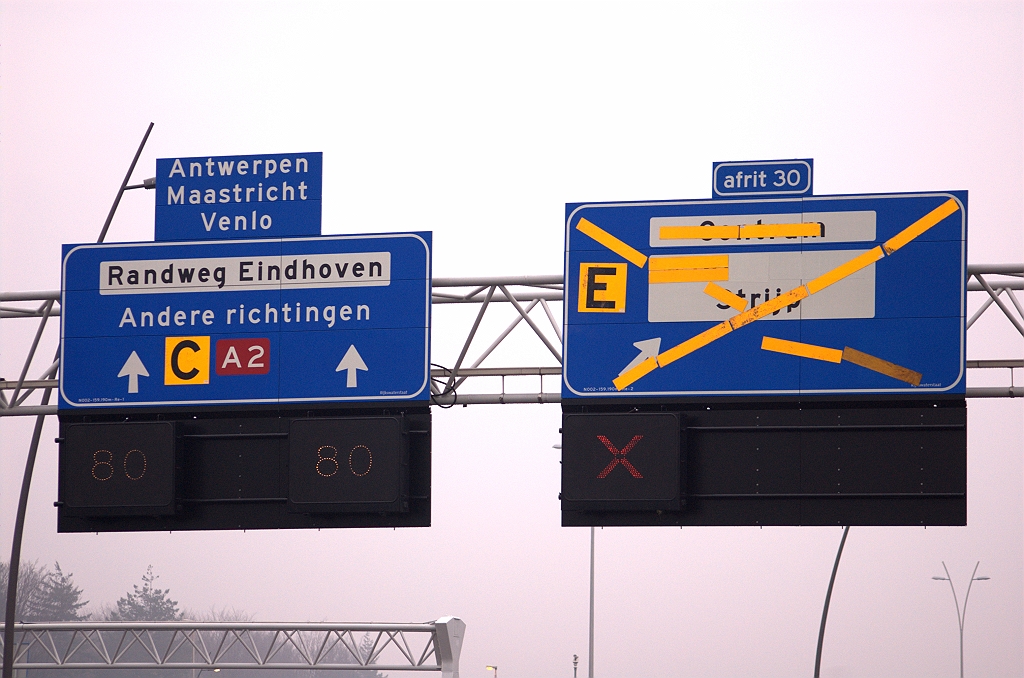 20081130-151340.jpg - Beslismoment aangebroken: pijlen wordt kort, en kromme pijl wordt schuinstaand pijltje. Hier is de industriebewegwijzering ook nog eens met wit overgeplakt, in tegenstelling tot op het 500 meter bord. Bij de openstelling van de nieuwe aansluiting Strijp, twee weken na fotodatum, verwijderd men de gele magneten, maar naar verwachting niet de witte overplakker. De industrie zou dan wel op het 500 meter bord worden aangegeven, maar niet op het bord erna.