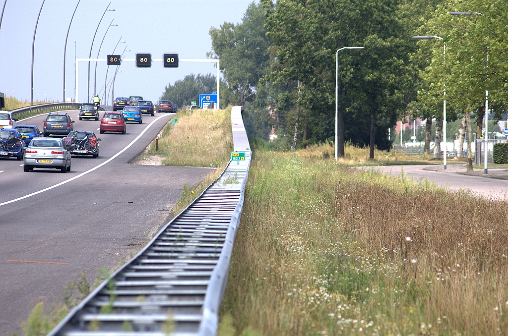 20090816-144430.bmp - Begin van de afrit op de N2, die zodanig lijkt te liggen dat hij in eerste instantie meestijgt met de helling naar KW 14 alvorens te divergeren. De ruimtebesparing die daarmee bereikt wordt zou de Hoevenweg een voortijdig doodlopen bespaard blijven, zodat alle bedrijfspercelen aan die weg hun ontsluiting behouden. De aansluiting Meerenakkerweg bevindt zich nog in de procedurefase. Er is nog niet eens een OTB. Misschien wat ongelukkig is het lot van de aansluiting verbonden aan dat van de aansluiting Veldhoven, waar een  ontvlechting  wordt voorgestaan door de gemeenten. Maar daar is het laatste woord  nog niet over gezegd .