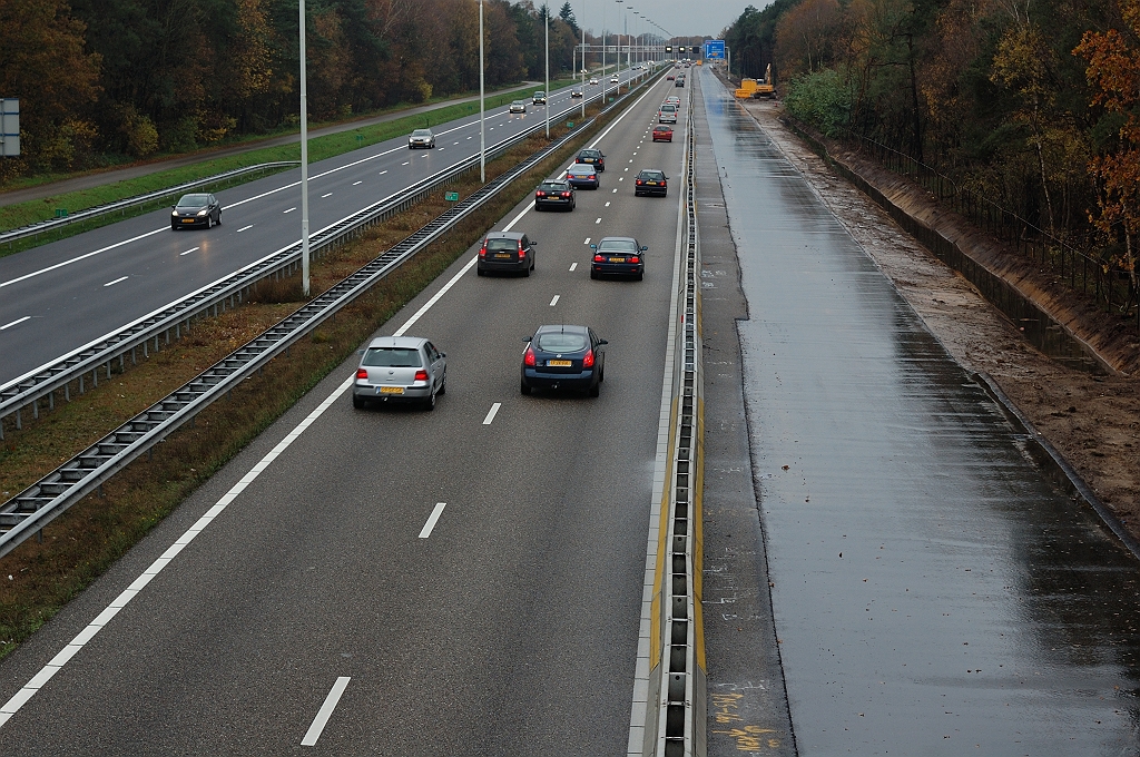 20101114-150753.JPG - Bermsloot past dan weer niet onder het viaduct, zodat we aan de westzijde de overgang zien tussen de asfalten "richel", met kolken voor lozing op een rioolbuis, en het vervolg van de bermsloot. Bij de verspringing in het afgefreesde bestaande vluchtstrook-ZOAB moet zo ongeveer de rijbaanbrede her-overlaging met dubbellaags ZOAB beginnen.  week 201043 