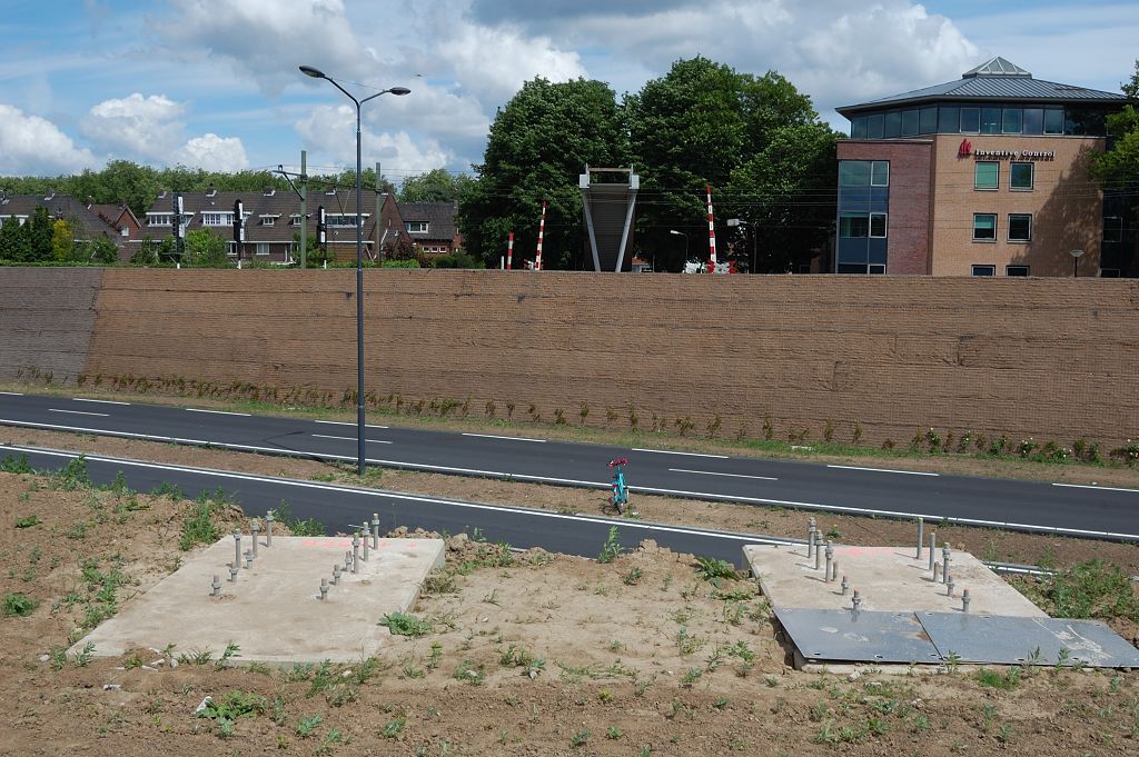 20110515-134725.JPG - In die aarden wal liggen nog wat nieuwe funderingen te wachten op een toepassing. Dat lijkt een voetgangersbrug te worden, gezien het bouwsel aan de andere kant van de spoorlijn. Die moet dus wel een meter of 8 hoog worden om de bovenleiding te overstijgen. Hij komt op de plaats van de door de Randweg onderbroken Isabellaweg. Je kan de slagbomen nog zien van de (in onbruik geraakte?) spoorwegovergang.