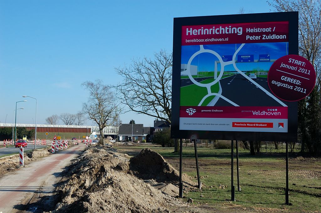20110320-154803.JPG - Op het bouwbord zien we ook een impressie van de voertuigkerende portalen, zodat te hoge voertuigen niet de hangende fietsrotonde kunnen aanrijden.