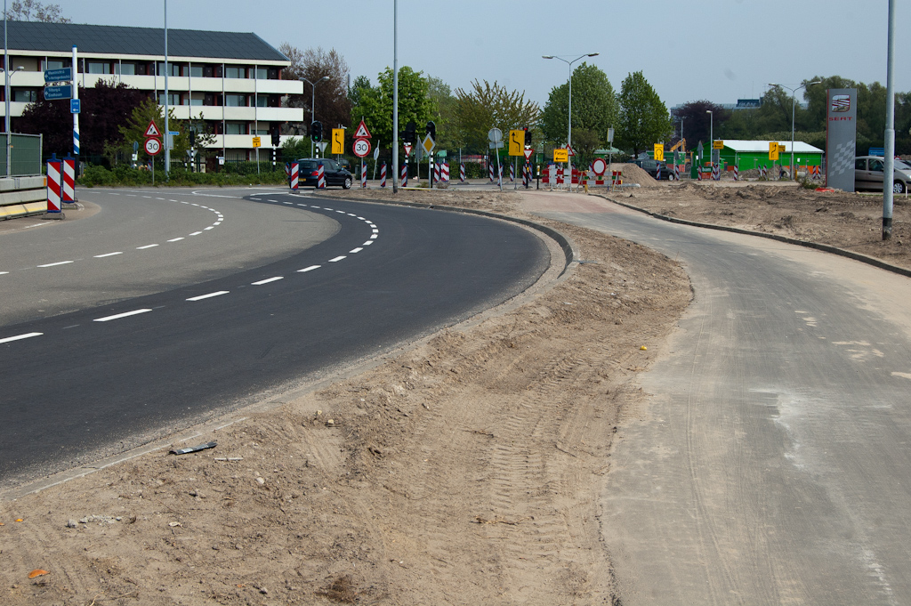 20110417-131749.jpg - En inderdaad is het zand voor het merendeel weggeveegd van het verlegde fietspad. Een mooi gebaar naar de fietsers, ook al gaat dit nieuwe asfalt allemaal weer weg als de ombouw naar kruispunt begint. Links op de foto nog net te zien dat de barrier is verplaatst, zodat er meer werkruimte in het rotonde-eiland is verkregen.  week 201114 